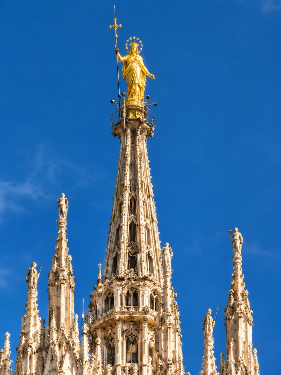 The great spire of Milan Cathedral with the gilded Madonnina statue against a blue sky
