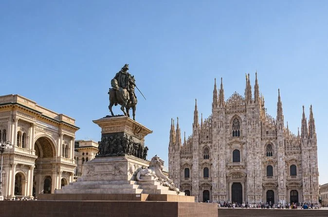 The equestrian statue of Victor Emmanuel II in Piazza del Duomo, with the white cathedral facade behind it under a clear sky