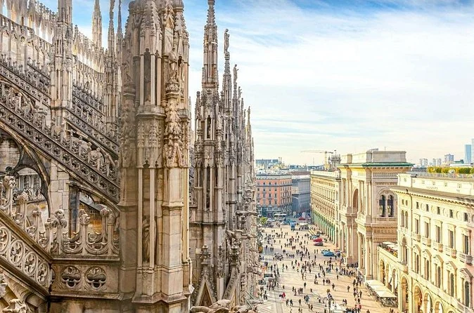 View from the cathedral roof past carved spires and flying buttresses down to the busy piazza and the Galleria building